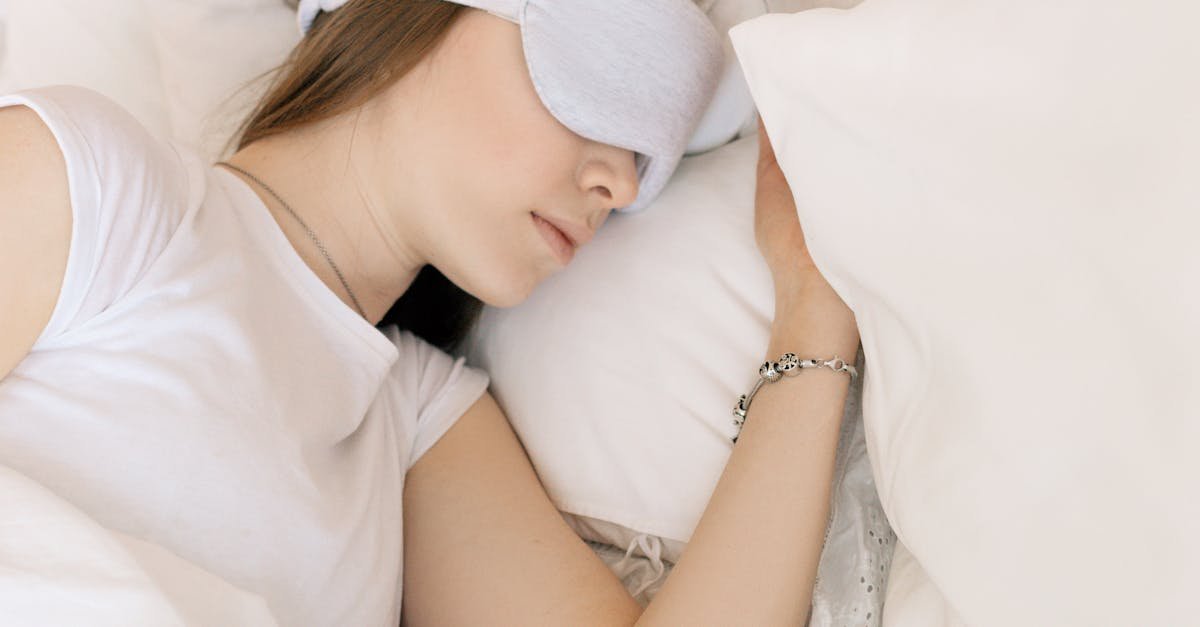 A serene scene of a woman sleeping with a white sleep mask in a cozy bed.